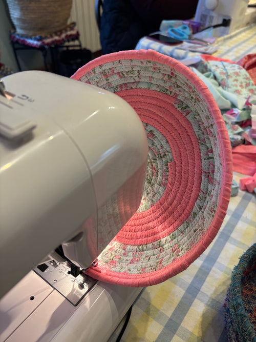 Sewing machine with a circular coiled cord bowl being worked on