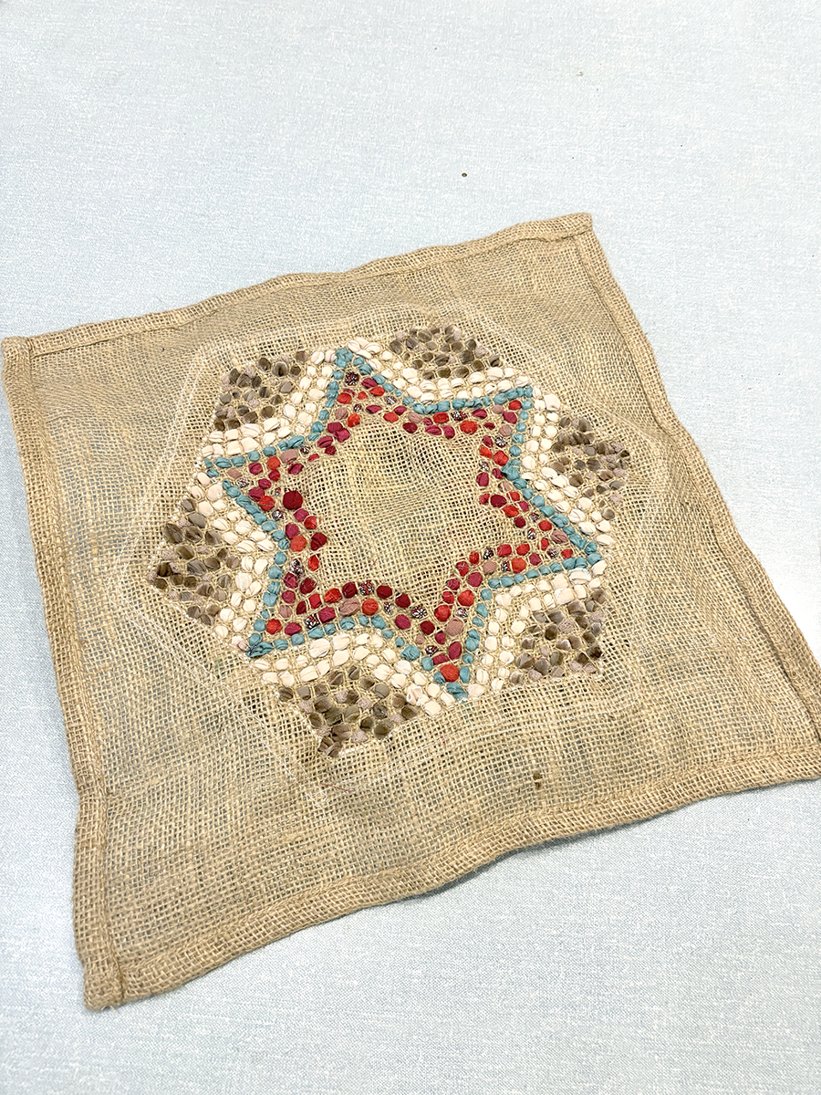 Back of short shaggy rag rugging showing rows of fabric pieces in a star shape