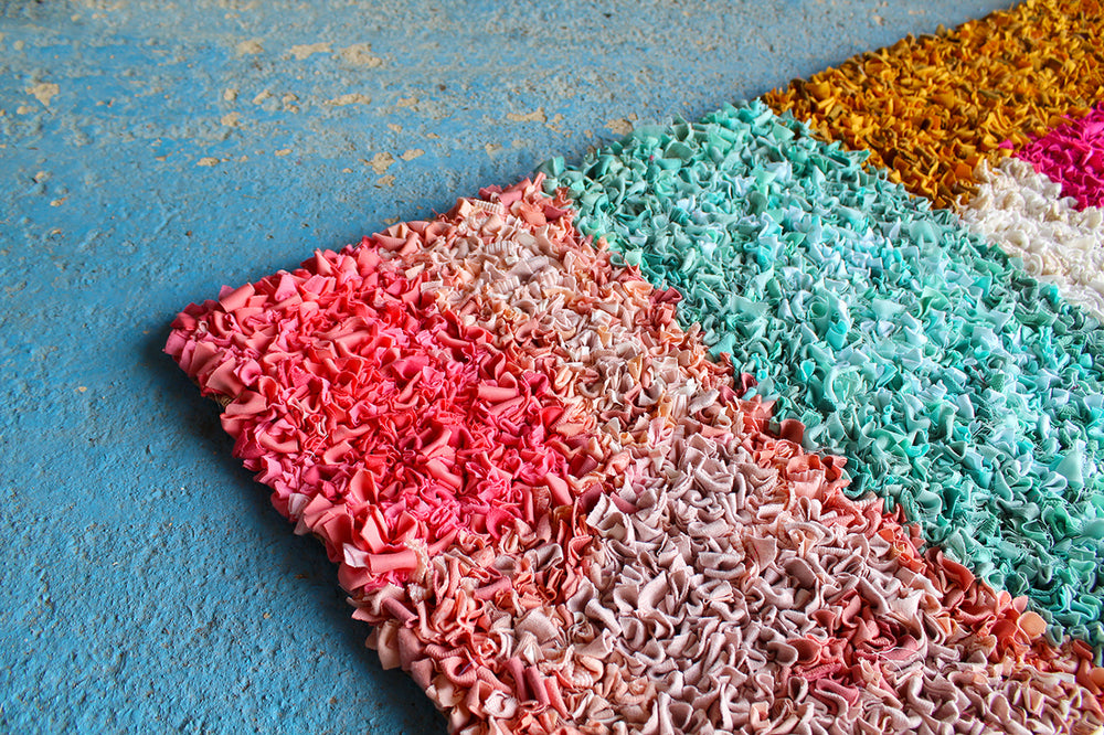Multicolored textured short shaggy rag rug on a blue surface 