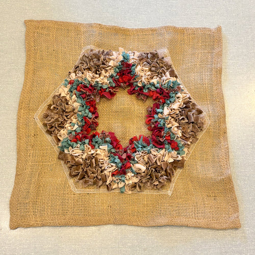 Red,  blue and brown rag rug star design on square piece of hemmed hessian / burlap