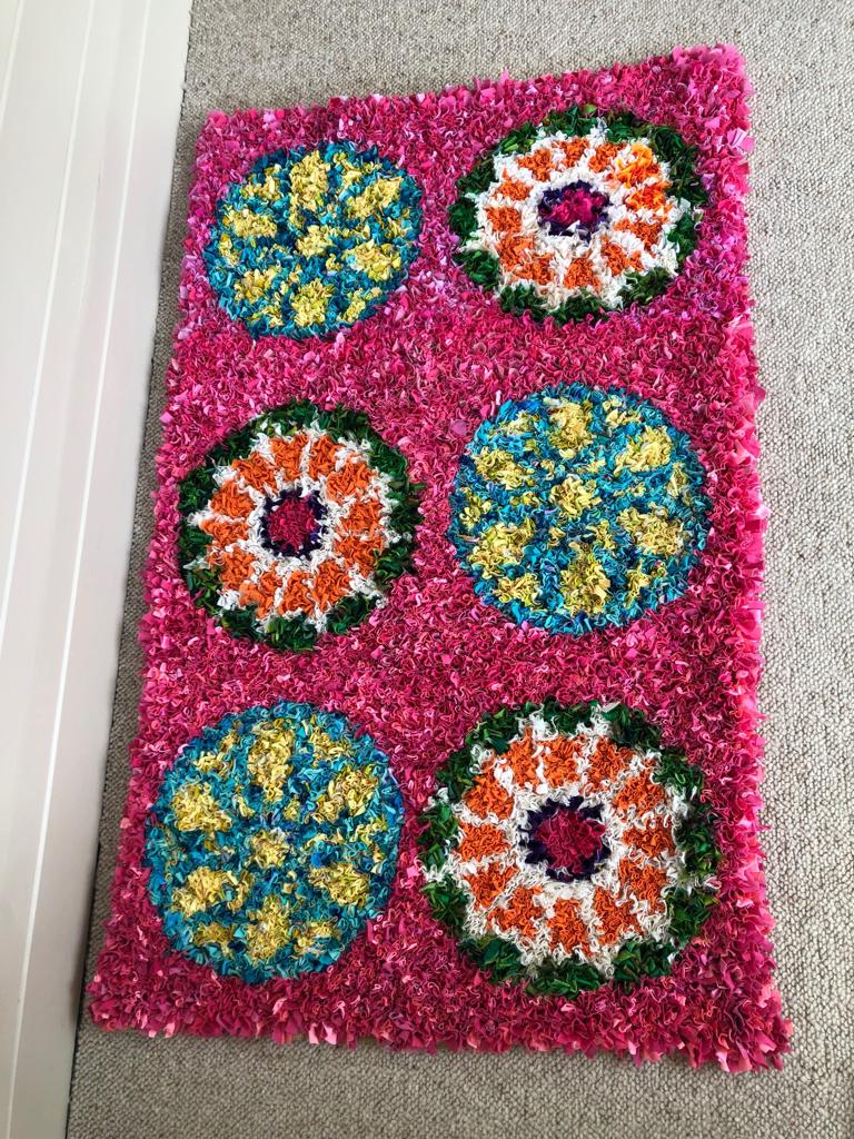 Pink, green, orange, blue and yellow rag rug with circular design inspired by stained glass windows