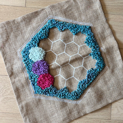 Hexagonal textured rag rug patch with colorful design on a burlap square rug backing