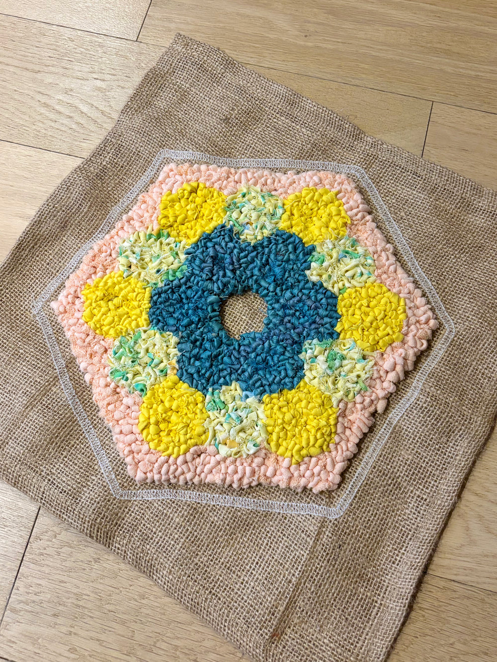 Hexagonal rug hooked rag rug with a floral pattern on a wooden floor