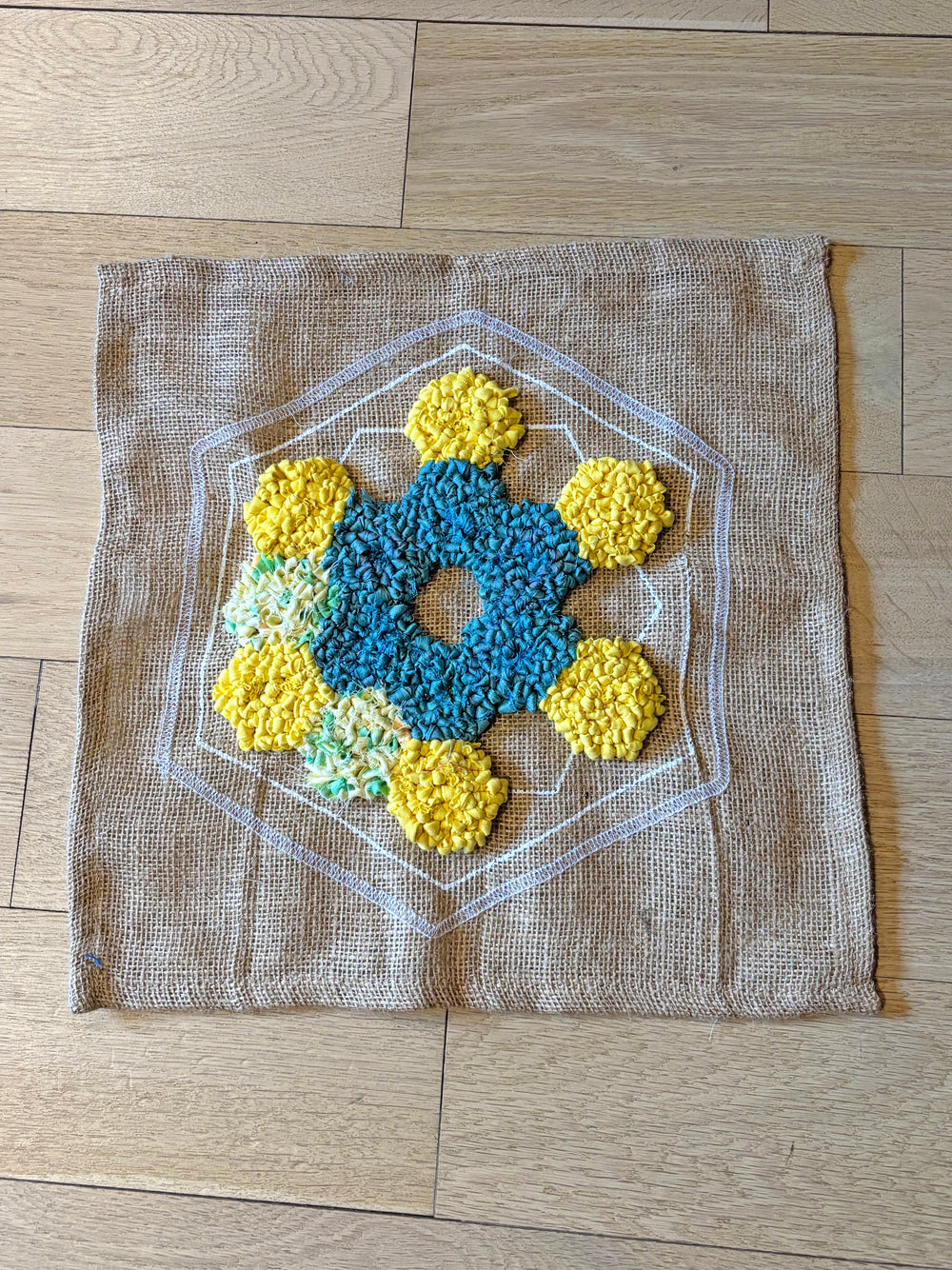 Partially rag rugged design on burlap rug base in yellow, blue and multicoloured fabrics