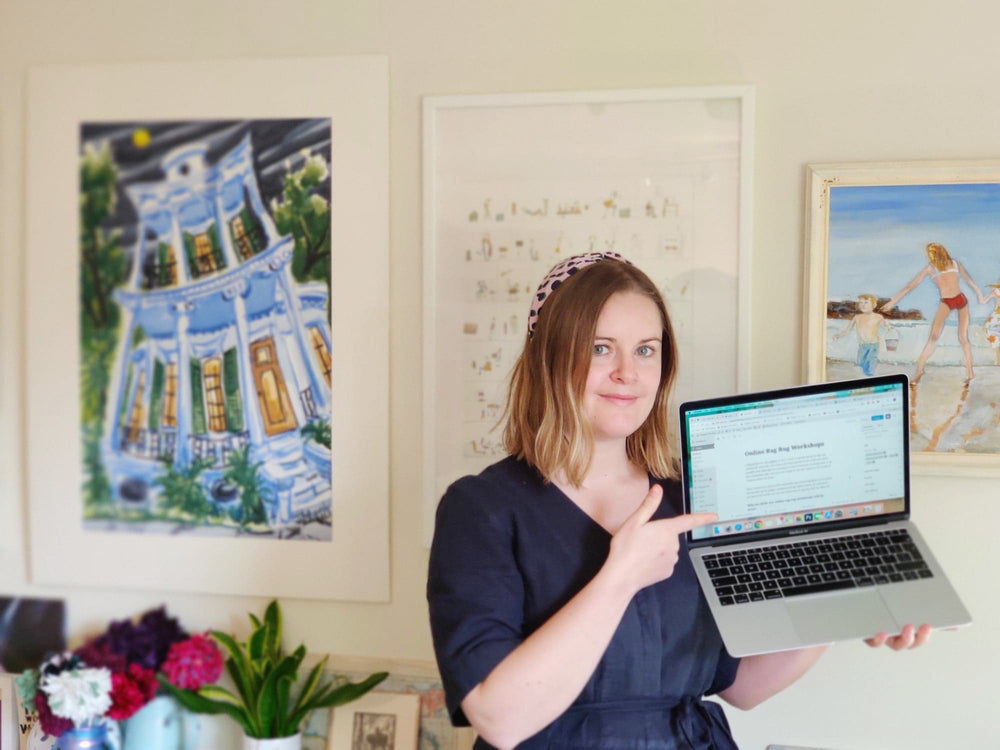 Elspeth Jackson from Ragged Life pointing at a laptop in front of artworks